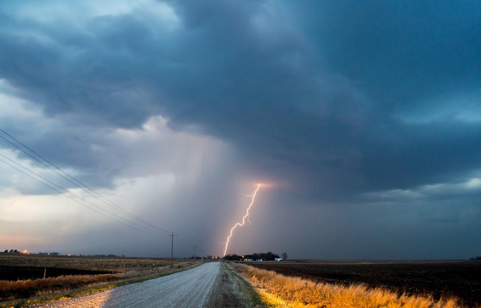 El Nino - A field under a dramatic stormy sky with lightning striking, representing the impacts of climate change and extreme weather conditions.